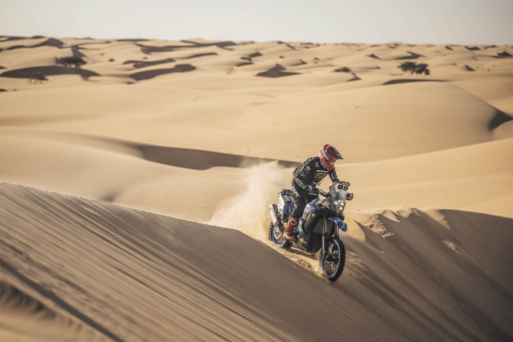 Thierry Traccan sur sa moto autour de dunes de sable