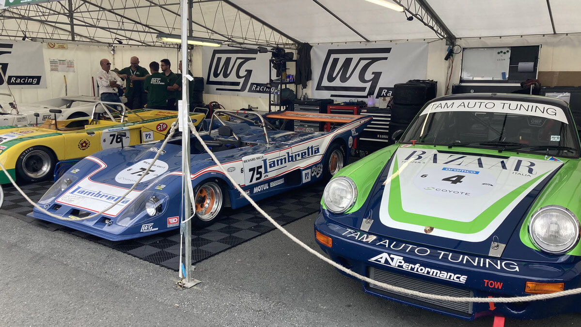 BMW et Porsche de course alignées dans les stands du Mans Classic.